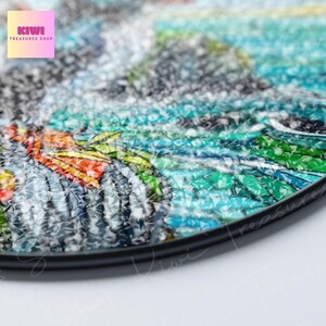 Puede incluir: Primer plano de un plato redondo de mosaico colorido con un borde negro. El dise&ntilde;o de mosaico presenta una variedad de colores, incluyendo azul, verde, amarillo, naranja y blanco. El plato est&aacute; hecho de vidrio y tiene una superficie texturizada.