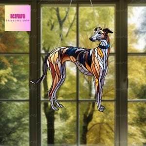 Puede incluir: Una ventana de vitral colgante presenta una ilustración colorida de un galgo. El perro está representado en una pose de pie con la cabeza girada hacia un lado. El vitral está hecho de pequeños trozos de vidrio en varios tonos de marrón, amarillo, azul y blanco.