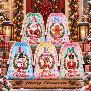 May include: Five fabric drawstring gift bags with a diamond pattern, each featuring a unique Christmas character: Santa, a gingerbread man, a snowman, a reindeer, and a nutcracker. Each bag displays a large letter, a wreath, and the text Merry Christmas.