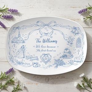 Puede incluir: Plato ovalado blanco con un dibujo lineal azul de ilustraciones temáticas de boda. El diseño incluye una iglesia, palomas, anillos de boda, pastel y el texto "The Williams". El texto también dice "Amamos porque Él nos amó primero."