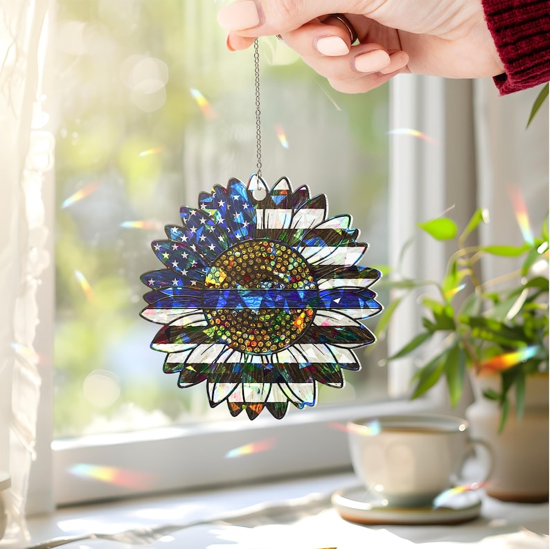 May include: A blue and white sunflower-shaped ornament with a thin blue line across the center. The ornament is hanging from a silver chain.