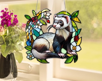 May include: A stained glass window hanging features a ferret sitting in a circle of colorful flowers. The ferret is white and brown with black markings. The flowers are yellow, pink, red, and blue.