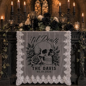 May include: A white lace table runner featuring a black graphic print of a human skull surrounded by roses. The text 'til Death' is printed above the skull, with 'THE DAVIS' and '05.19.2026' printed below in a bold, dark font style.