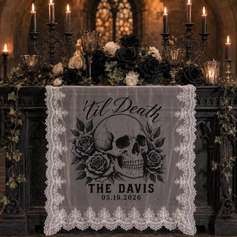 May include: A white lace table runner featuring a black graphic print of a human skull surrounded by roses. The text 'til Death' is printed above the skull, with 'THE DAVIS' and '05.19.2026' printed below in a bold, dark font style.