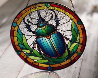 May include: A stained glass window hanging with a chain, featuring a colorful beetle with green, blue, and yellow accents, surrounded by green leaves and a multi-colored border.