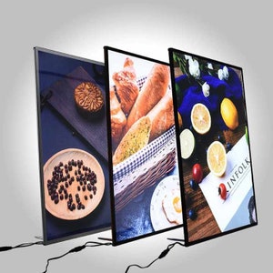 May include: Three black framed light boxes with different images. The first box shows a plate of black beans, the second box shows a basket of bread, and the third box shows lemons, blueberries, and a piece of paper with the text "INFOLK".
