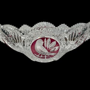May include: A clear glass bowl with a cut glass design and a red cameo of a bird with leaves. The bowl has two handles.