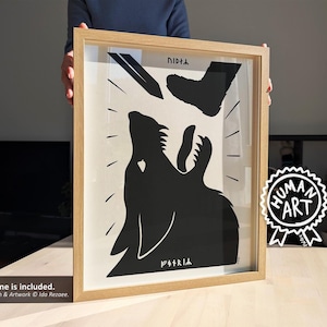 May include: A framed black and white art print featuring a howling wolf silhouette beneath a descending boot and a pen. The artwork includes the text "DIDTA" and "PIRRIA". A "HUMAN ART" sticker is visible.