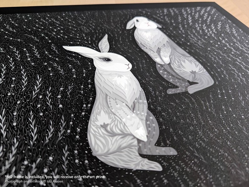 May include: An art print featuring two white rabbits with intricate grey patterns on their fur, set against a dark black background filled with detailed white botanical illustrations. The text at the bottom reads: NO frame is included, you will receive only the art print. Photograph and artwork &copy; Ida Rezaee.