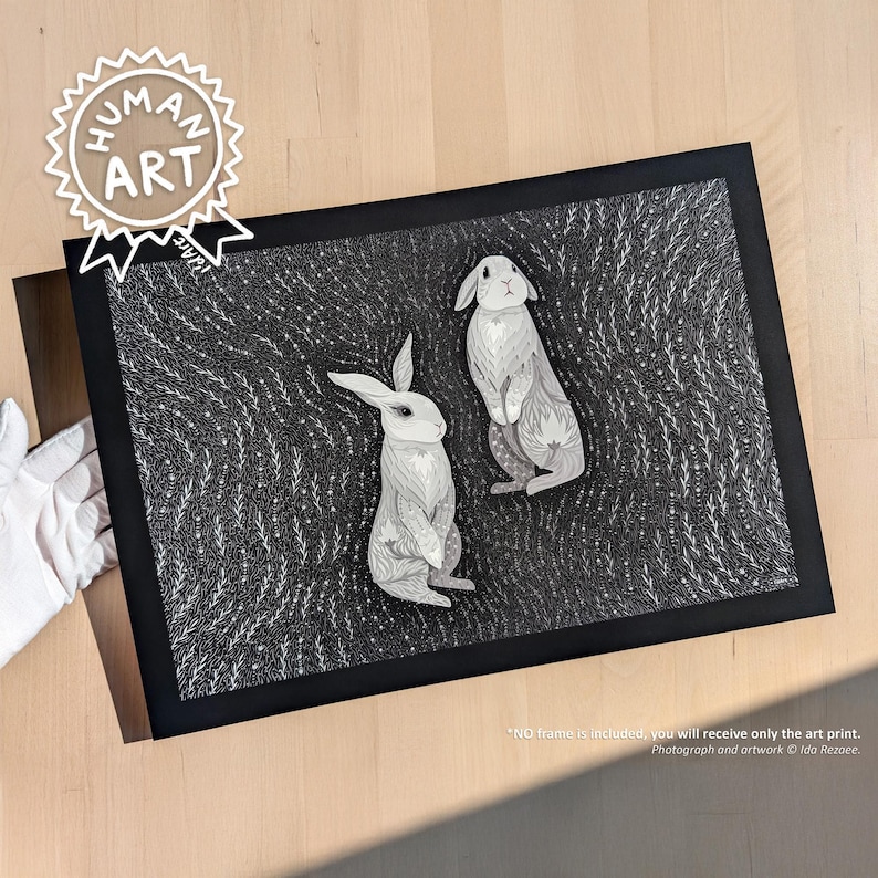 May include: A rectangular art print featuring two white rabbits illustrated with intricate line work against a dense, dark background of swirling white botanical patterns. The print is encased in a simple black border, showcasing a high-contrast design.