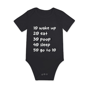 Puede incluir: Un body negro para bebé con texto blanco que dice "10 wake up, 20 eat, 30 poop, 40 sleep, 50 go to 10".