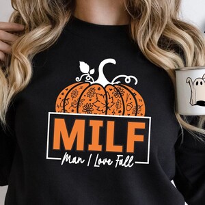 May include: Black sweatshirt with an orange pumpkin design and the text "MILF - man I love fall".