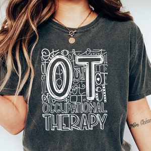 May include: A dark gray t-shirt with a white graphic design that says "OT of OT Occupational Therapy".