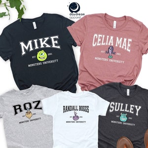 Puede incluir: Cinco camisetas con diferentes nombres de personajes de Monsters University. Las camisetas son azul marino, malva, gris, blanca y carb&oacute;n. Cada camiseta tiene el nombre de un personaje en una fuente universitaria, con una ilustraci&oacute;n de personaje de dibujos animados.