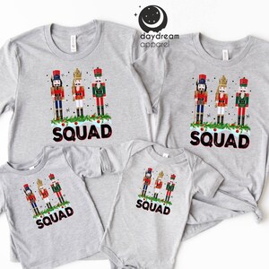 May include: A set of four grey t-shirts featuring a Christmas Nutcracker design with the word "SQUAD" printed on each shirt.