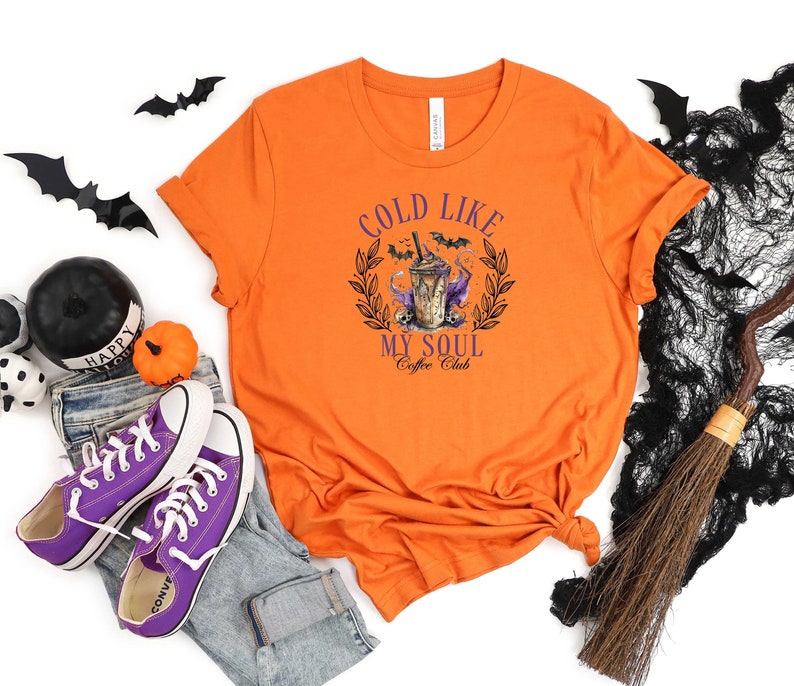 May include: Orange t-shirt with a graphic of a coffee drink with bats and the text "Cold Like My Soul Coffee Club".