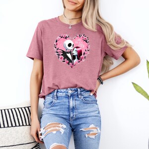 May include: A mauve-colored t-shirt featuring a heart-shaped graphic with Jack Skellington and Sally from The Nightmare Before Christmas. The heart is surrounded by pink roses and the text "Love You Death".