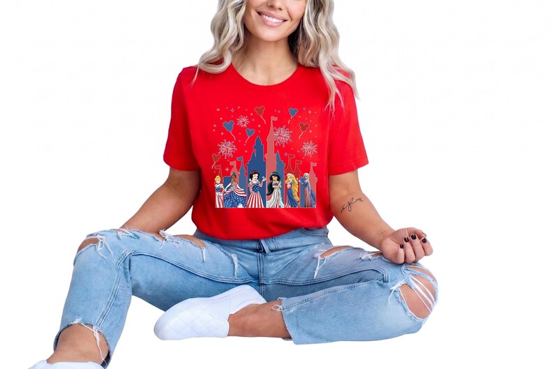 K&ouml;nnte beinhalten: Ein rotes T-Shirt mit einem Schlossdesign, Feuerwerk und Zeichentrickfiguren in patriotischer Kleidung. Das Shirt wird mit hellblauen zerrissenen Jeans und wei&szlig;en Schuhen kombiniert. Das Design hat ein festliches Thema.