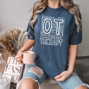 May include: A navy blue t-shirt with a white graphic design that says "OT Occupational Therapy" with a large white "OT" in the center.