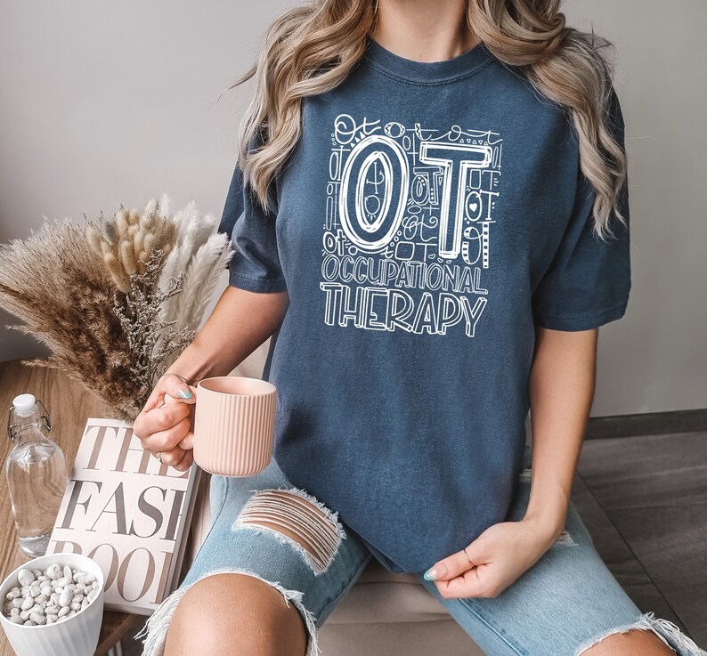 May include: A navy blue t-shirt with a white graphic design that says "OT Occupational Therapy" with a large white "OT" in the center.
