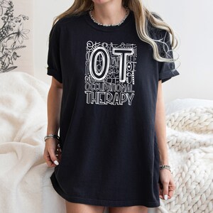 May include: A black t-shirt with a white graphic design that says "OT Occupational Therapy" with the letters "OT" in a larger font size.