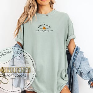 May include: A light green t-shirt with the text "Pumpkin Spice and everything nice" and a small pumpkin graphic. The shirt is part of the "Embroidered Comfort Colors" collection and is a personalized gift.
