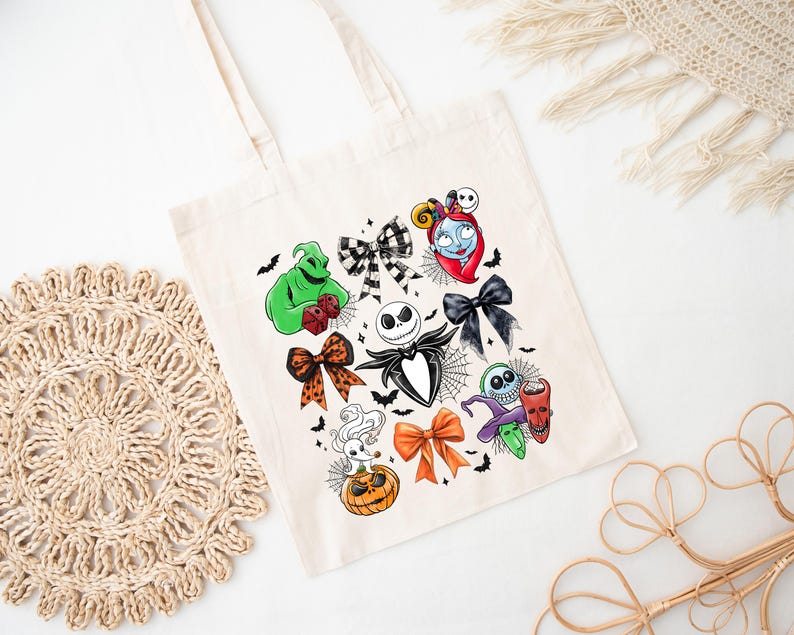 May include: A cream-colored tote bag featuring colorful illustrations of characters and bows from a popular animated film. The design includes Jack Skellington, Sally, and Oogie Boogie, with bats and spiderwebs. The bag has two handles.