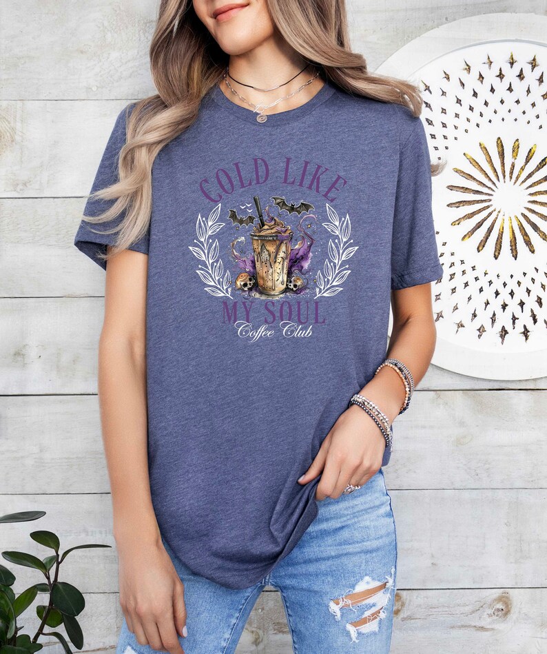 May include: A heather blue t-shirt with a graphic of a coffee cup with bats and the text "Cold Like My Soul Coffee Club".