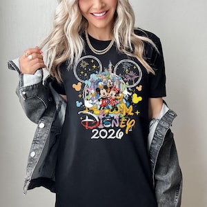 May include: Black t-shirt featuring a colorful Disney design with Mickey and Minnie Mouse, Donald Duck, and other characters. The shirt includes the text "Disney 2026" in a playful font, with fireworks and a castle graphic.