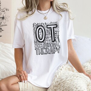 May include: White t-shirt with a black and white graphic design that says "OT Occupational Therapy".