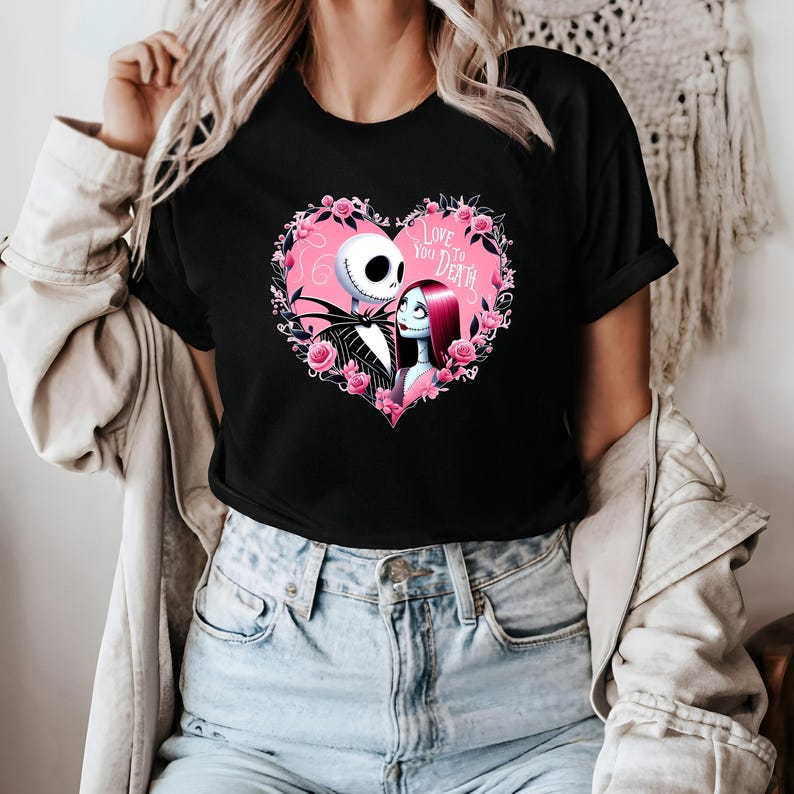 May include: Black t-shirt featuring a heart-shaped design with Jack Skellington and Sally from The Nightmare Before Christmas. The pink heart is surrounded by pink roses and the text "Love You to Death".