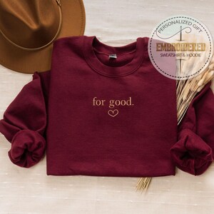 May include: Burgundy sweatshirt with the text "for good." embroidered in gold with a small heart below the text.