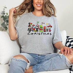 May include: A gray t-shirt with a graphic of characters from the Nightmare Before Christmas movie. The characters are arranged in a line and the text "CHRISTMAS" is below them.