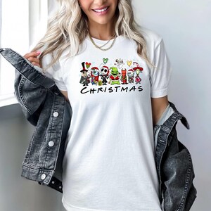 May include: White t-shirt with a graphic of characters from The Nightmare Before Christmas. The characters are standing in a line and the text "CHRISTMAS" is below them.