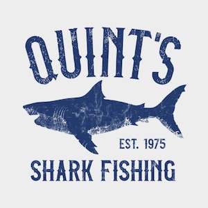 Puede incluir: Un diseño gráfico azul y blanco desgastado con el texto "Quint's Shark Fishing Est. 1975" y una silueta de un tiburón.