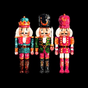 May include: Three wooden nutcracker figurines, each with a different design. The first is wearing a blue and green suit with a crown, the second is wearing a green suit with a black hat, and the third is wearing a pink suit with a red hat.