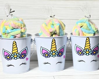 May include: Three small blue metal buckets with unicorn designs and pink, yellow, and blue flowers. Each bucket contains a clear plastic bag filled with colorful pastel marshmallow swirls.