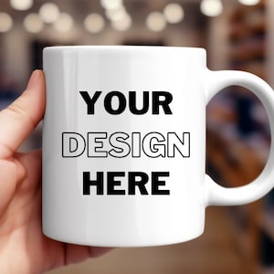 May include: White ceramic mug with a black outline of the words "YOUR DESIGN HERE" printed on the front.