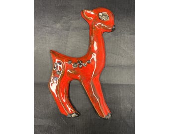 May include: A red ceramic deer figurine with black accents. The deer is standing on all four legs and has a long neck.