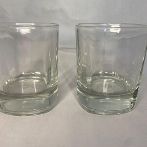 Puede incluir: Dos vasos transparentes de vidrio con forma cuadrada y base gruesa.