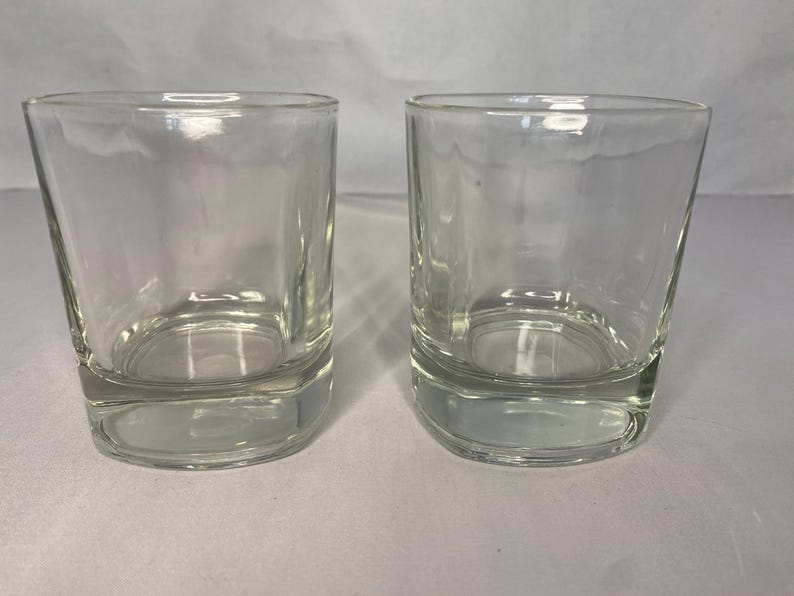 Puede incluir: Dos vasos transparentes de vidrio con forma cuadrada y base gruesa.