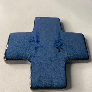K&ouml;nnte beinhalten: Ein blaues Keramikkreuz mit einer strukturierten Oberfl&auml;che.