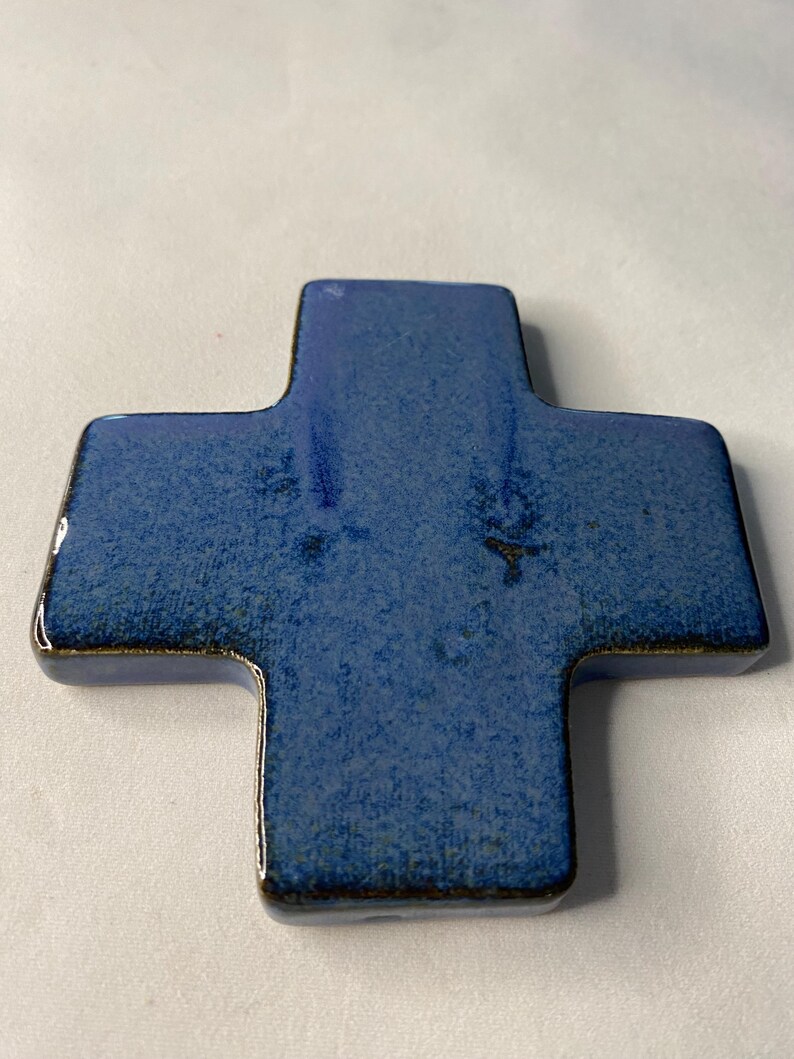 K&ouml;nnte beinhalten: Ein blaues Keramikkreuz mit einer strukturierten Oberfl&auml;che.