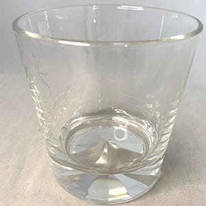 Puede incluir: Un vaso de vidrio transparente y vac&iacute;o con una base facetada y un borde ligeramente ensanchado. El vaso tiene un dise&ntilde;o grabado en el lateral. El vaso est&aacute; dise&ntilde;ado para beber bebidas.