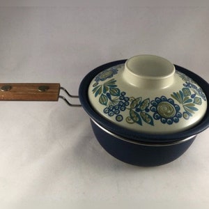 以下が含まれることがあります： 青い花柄のエナメル製の鍋で、木製の取っ手が付いています。蓋は白いノブが付いていて、花柄のデザインです。