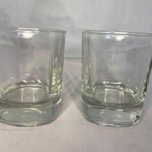 Puede incluir: Dos vasos transparentes de vidrio, cada uno con un fondo redondeado y lados rectos. Los vasos est&aacute;n vac&iacute;os y parecen estar hechos de vidrio grueso.
