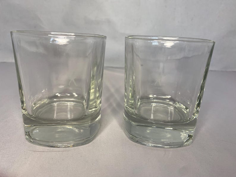 Puede incluir: Dos vasos transparentes de vidrio, cada uno con un fondo redondeado y lados rectos. Los vasos est&aacute;n vac&iacute;os y parecen estar hechos de vidrio grueso.