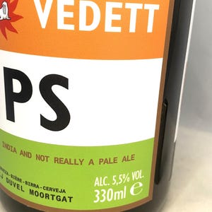 May include: A close-up of a beer bottle with a label featuring the word "VEDETT" in white on an orange background. The label also includes the text "PS" in black, and "INDIA AND NOT REALLY A PALE ALE". The bottle contains 330ml.