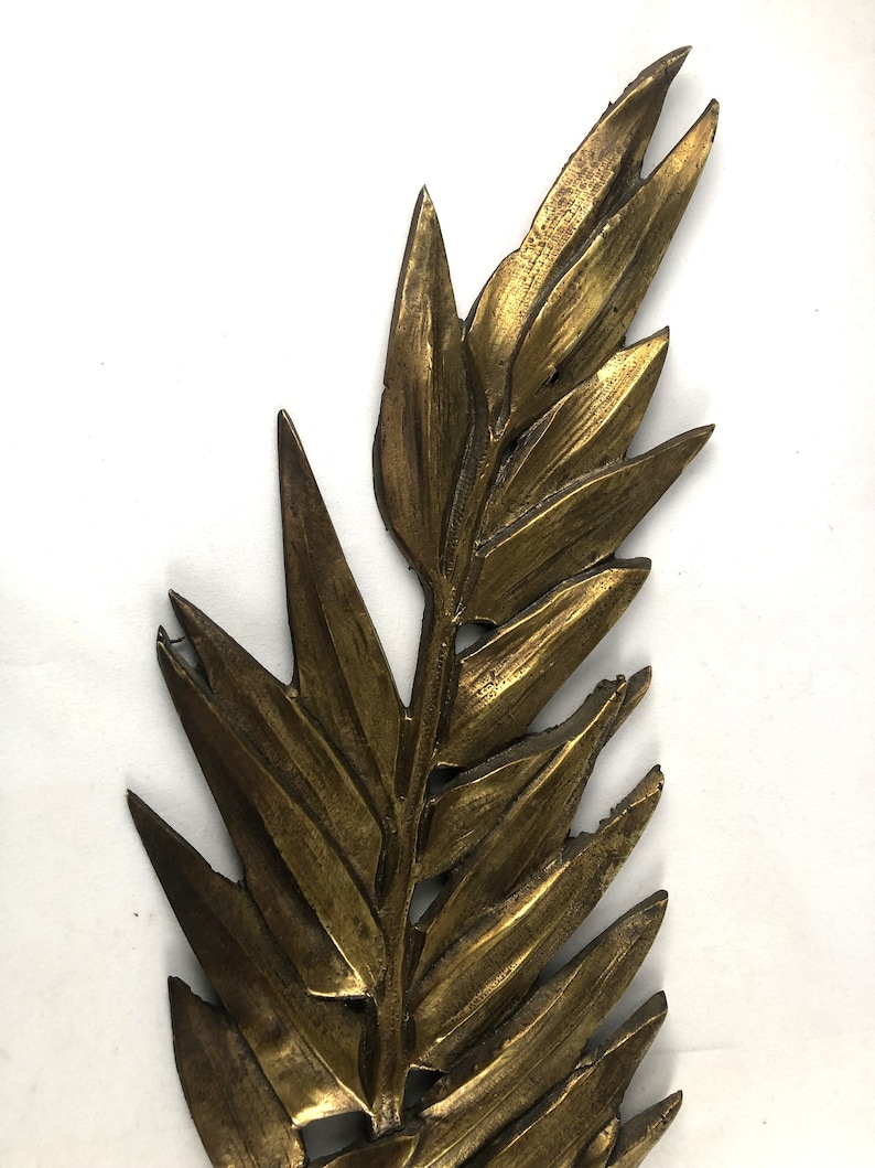 May include: A gold-colored metal leaf design with a detailed, textured surface. The leaf is a decorative element that could be used for a variety of purposes, such as a wall hanging or a craft project.