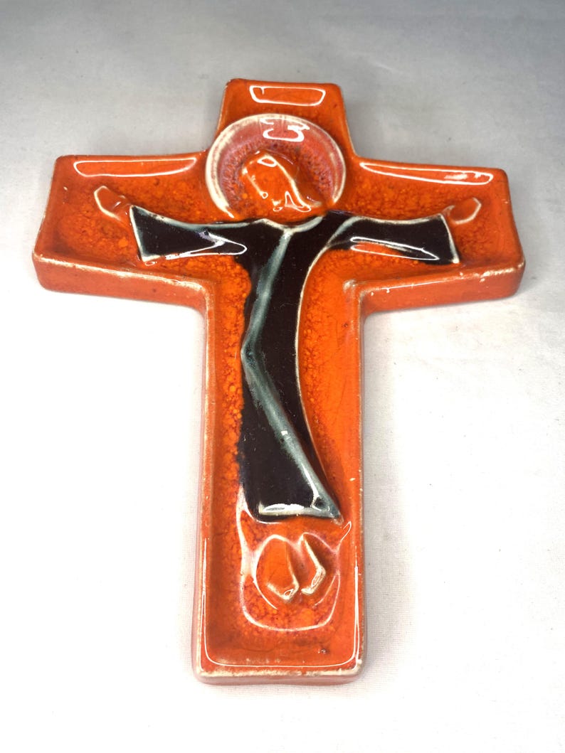 May include: Orange ceramic wall cross with a black and white figure of Jesus Christ on it.